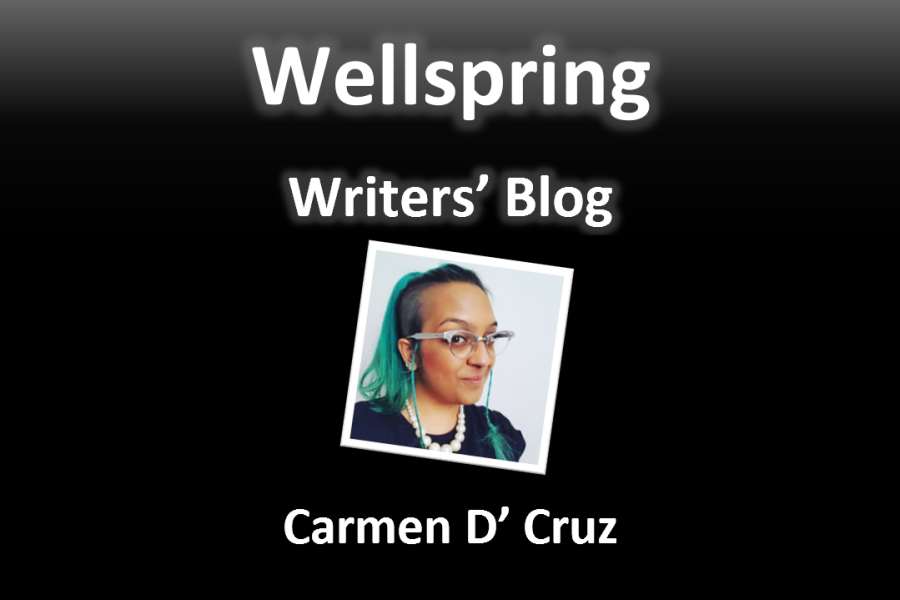 White letters on black background read 'Wellspring Writers' Blog'. Underneath a framed portrait photo a grinning brown skinned femme with bright green hair in a high ponytail, wearing silver Dame Edna style glasses and a pearl necklace over a black t-shirt. Underneath the photo, the name Carmen D’ Cruz is written in white letters.