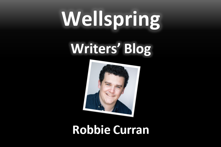 White letters on black background read 'Wellspring Writers' Blog'. Underneath a framed portrait photo of a white man with short dark curly hair, and he is giving a smile that shows his teeth and makes his eyes squinty. Underneath the photo, the name Robbie Curran is written in white letters.