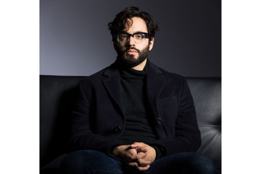 Man in his mid-thirties with olive skin, dark hair, short beard, and glasses.