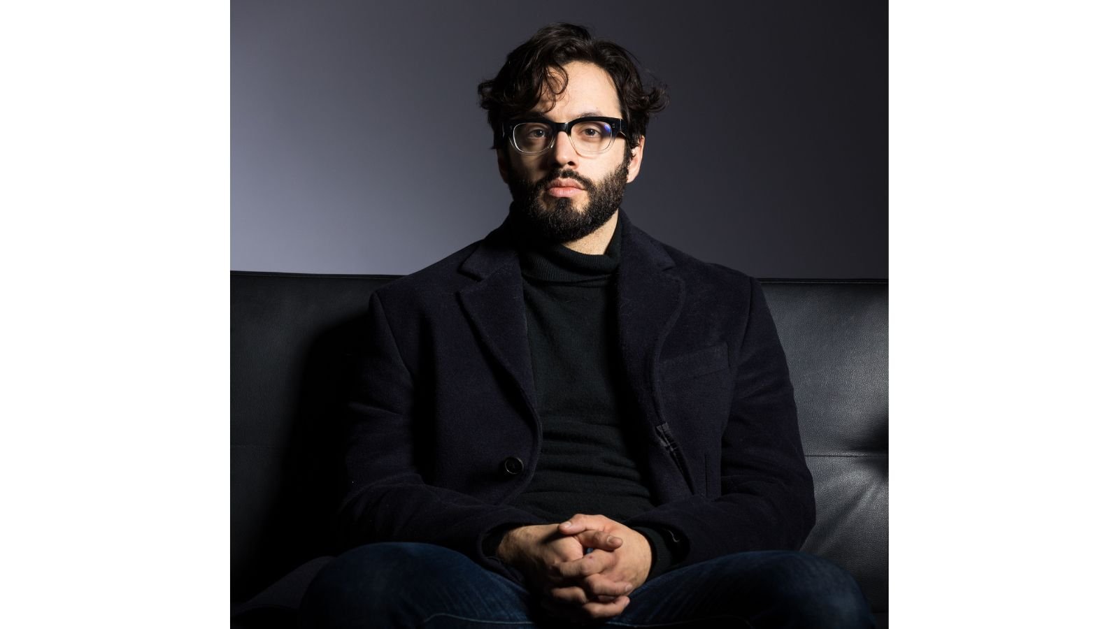 Man in his mid-thirties with olive skin, dark hair, short beard, and glasses.