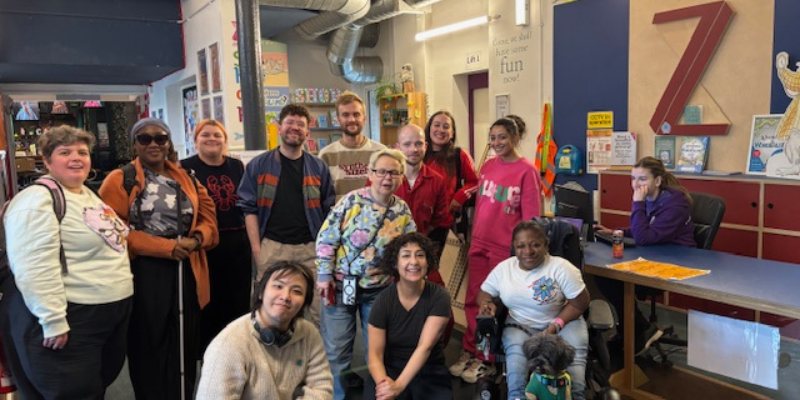 Group photo of 12 people of mixed ages, and ethnicities, smiling and laughing at the camera.